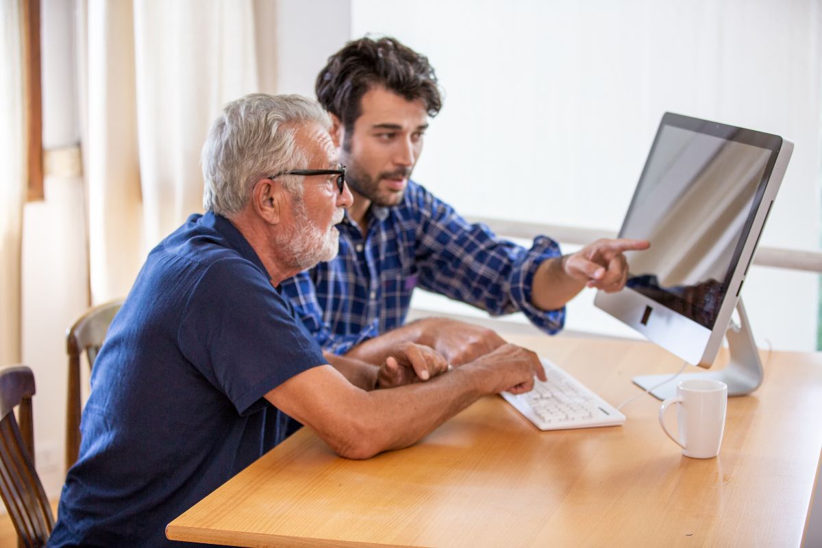 Younger person helping Medicare beneficiary understand Medicare on a computer